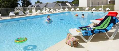 Ein Schwimmbecken mit Liegestühlen und ein Liegestuhl am Pool mit Handtuch.