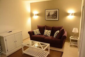 A living room with a brown sofa, white coffee table, and a picture on the wall.