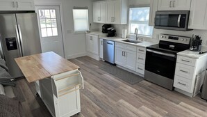 Una cocina moderna con armarios blancos, electrodomésticos de acero inoxidable y una mesa de madera.