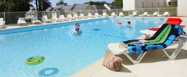 Ein Schwimmbecken mit Liegestühlen und ein Liegestuhl am Pool mit Handtuch.