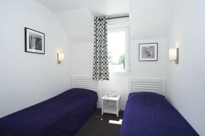 A small, clean room with two single beds, a window with a polka dot curtain, and two wall-mounted light fixtures. - ZEcamping 3 étoiles piscine couverte locatif TV LV BBQ 46m2 6 pers (Audierne)