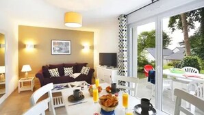 A modern living room with a sofa, a TV, and a dining area with breakfast items.