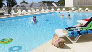 A swimming pool with lounge chairs and a poolside chair with a towel.