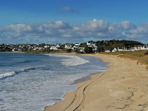 A beach with a sandy shore and a row of houses in the background. - ZEcamping 3 étoiles piscine couverte locatif TV LV BBQ 46m2 6 pers (Audierne)