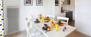 A dining area with a table set for breakfast, including croissants, fruit, and juice.