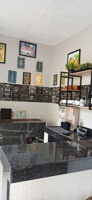 A bar area with a counter, shelves with glasses, and a wall decorated with various signs and pictures.