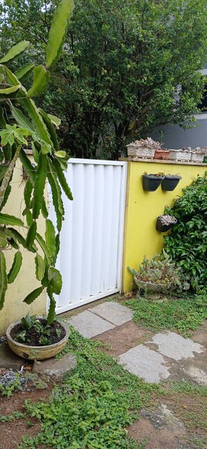 A garden with a white fence, potted plants, and a variety of greenery. - Beija Flor Suite for Couples with Pool Access in Cabo Frio, 25 minutes from Búzios. (Dunas do Peró Cabo Frio)
