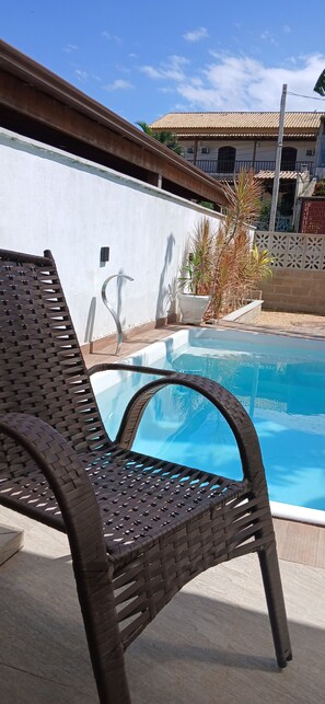A pool area with a chair and a white wall. - Beija Flor Suite for Couples with Pool Access in Cabo Frio, 25 minutes from Búzios. (Dunas do Peró Cabo Frio)