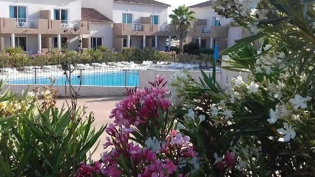 Een hotel met een zwembad, omringd door groen en bloemen.