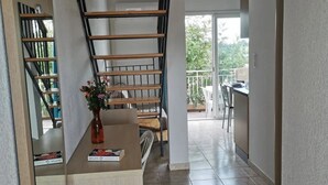 Un intérieur moderne avec un escalier en bois, une petite table ornée d’un vase et une vue sur un balcon.