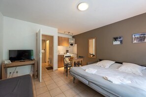 A hotel room with a bed, a desk with a television, a kitchenette, and a bathroom. - ZEcamping 3 étoiles dog friendly piscine couverte (Saumur)
