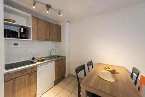 A compact kitchen with a dishwasher, a sink, and a dining table with chairs.