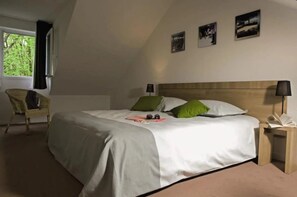 A bedroom with a bed, two pillows, a chair, a nightstand, and a window.
