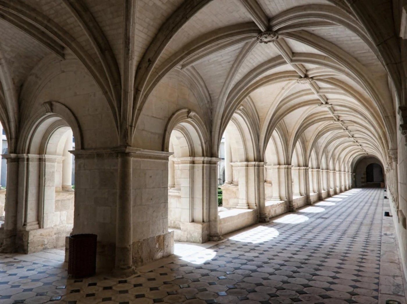 A long corridor with a series of arches and columns, leading to a distant end.