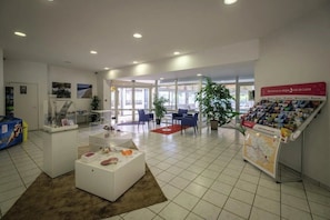 A spacious lobby with a reception desk, seating area, and informational displays.