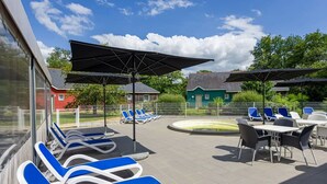 Een zwembadgedeelte met ligbedden, parasols en een klein zwembad.