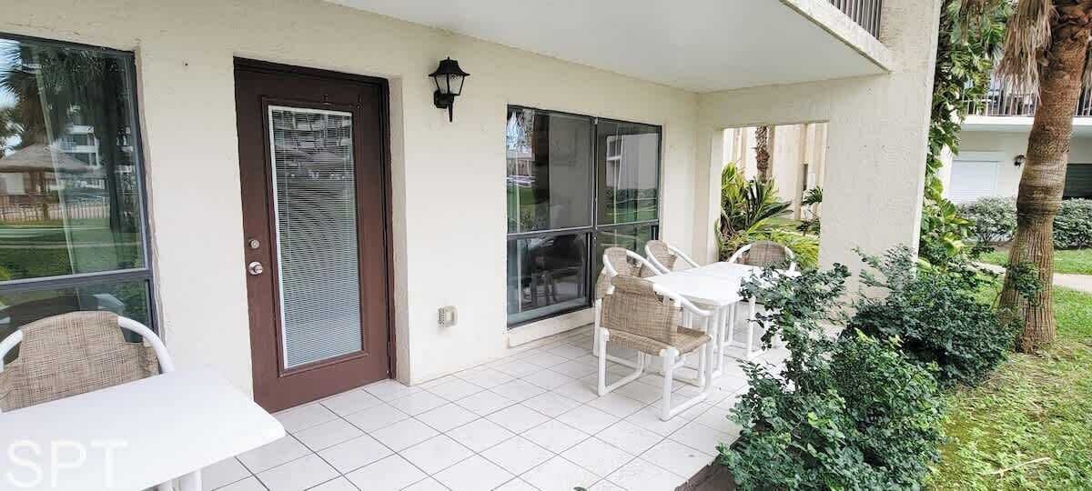 A covered patio with a table and chairs, a sliding glass door, and a small garden area with plants.