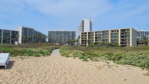 A pathway leading to a modern building complex with multiple floors and balconies. - Resort-like Beachfront - Heated Pool (South Padre Island)