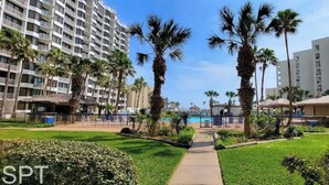 A hotel with a pool, palm trees, and a clear sky. - Resort-like Beachfront - Heated Pool (South Padre Island)