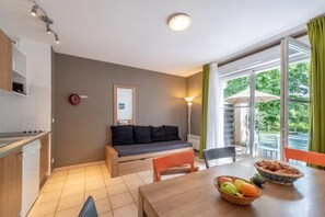Ein modernes Wohnzimmer mit Sofa, Esstisch und Küchenzeile.