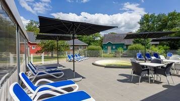 A poolside area with lounge chairs, umbrellas, and a small pool.