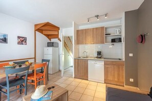 A compact kitchen with wooden cabinets, a white dishwasher, and a microwave.