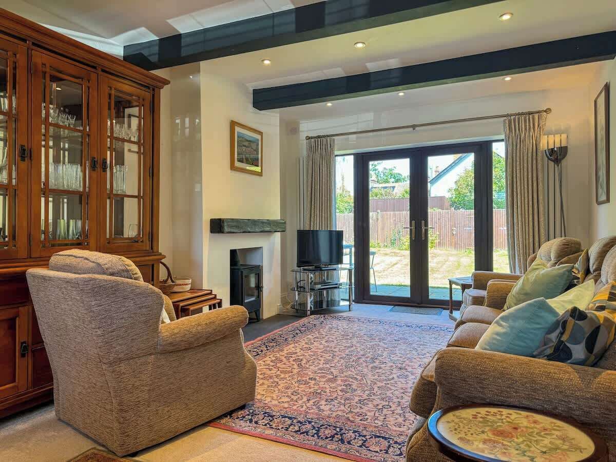 Cozy up in this inviting living room featuring plush, comfortable sofas, a sleek TV setup, and a warm, glowing fire pit—perfect for relaxing evenings at home.