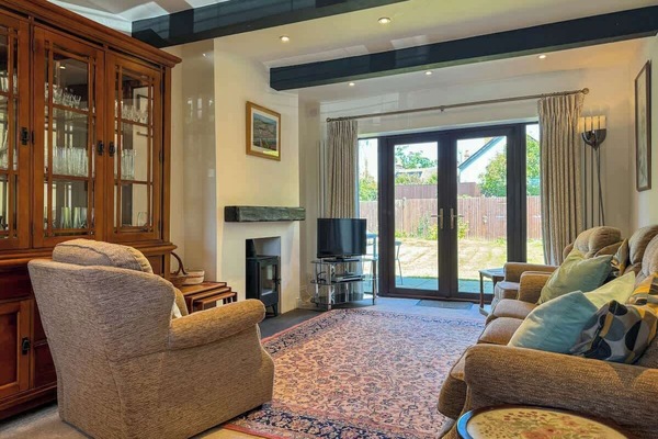 Cozy up in this inviting living room featuring plush, comfortable sofas, a sleek TV setup, and a warm, glowing fire pit—perfect for relaxing evenings at home.