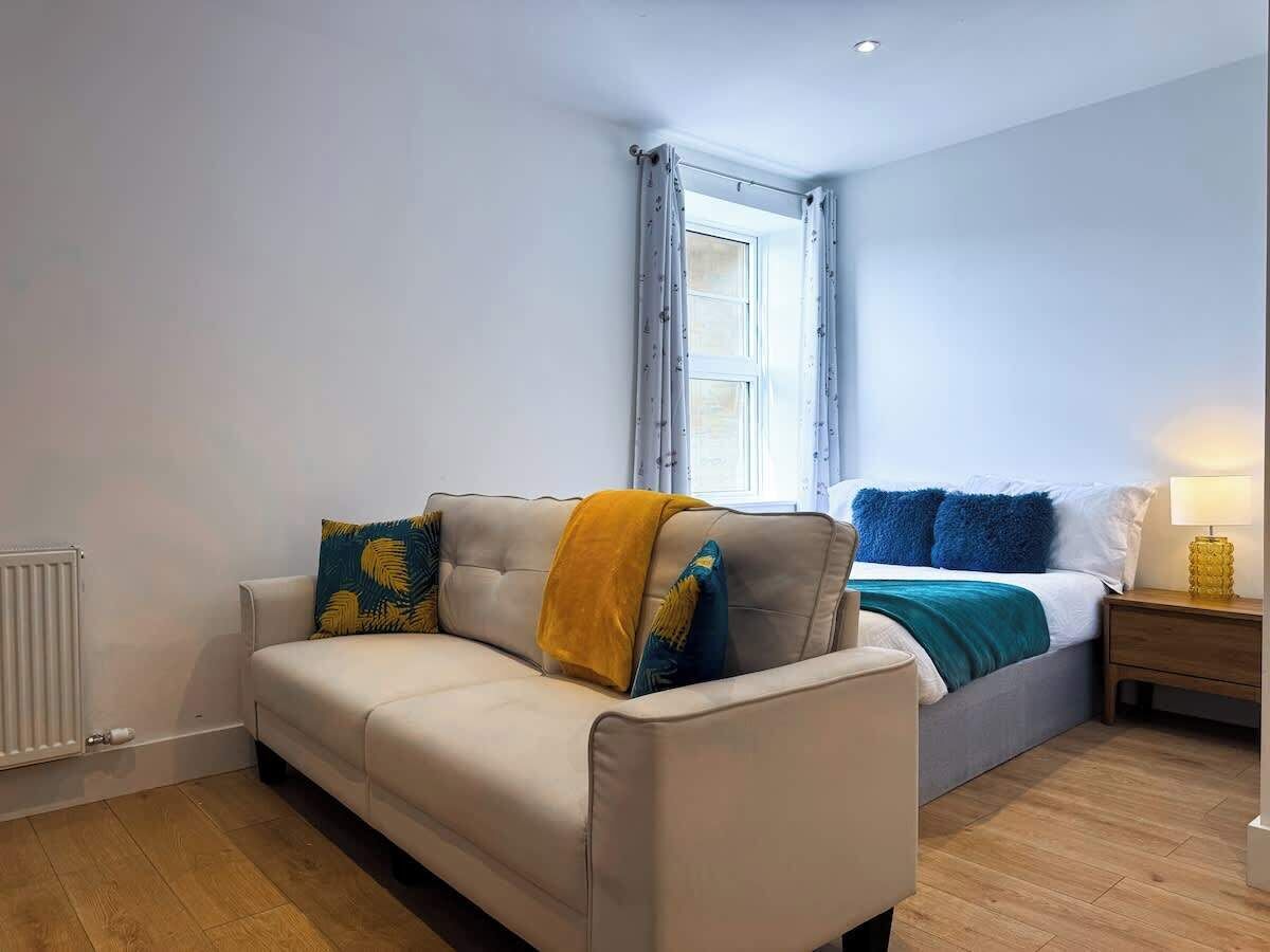 A bedroom with comfortable bed, sofa and a large window for natural light.