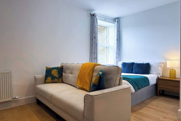 A bedroom with comfortable bed, sofa and a large window for natural light.