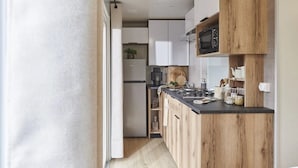 Een moderne keuken met houten kastjes, een zwart aanrecht en een magnetron.