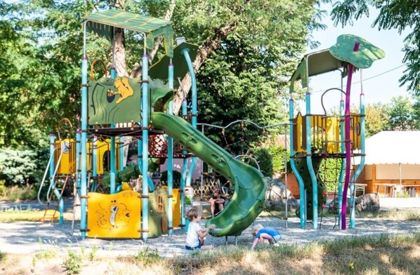 Ein Spielplatz mit Rutsche, Klettergerüsten und einem überdachten Spielbereich.