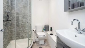 A modern bathroom with a glass-enclosed shower, a white toilet, and a large sink with a mirror. - Relaxing Annexe | With Garden Access & Parking (Kent)