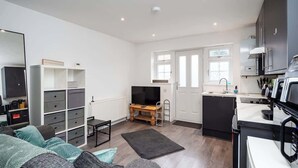 A compact living space with a kitchenette, a sofa, a TV, and storage units. - Relaxing Annexe | With Garden Access & Parking (Kent)