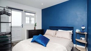 A bedroom with a bed, a nightstand, a dresser, a window, and a door. - Relaxing Annexe | With Garden Access & Parking (Kent)