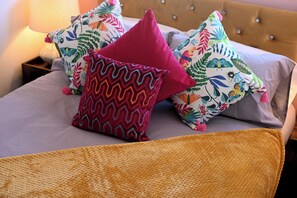 A bed with multiple colorful pillows and a textured blanket.