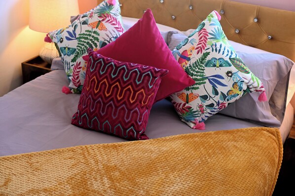 Una cama con varios cojines de colores y una manta con textura.