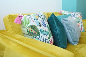 A yellow sofa with colorful patterned pillows.
