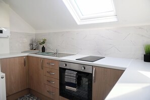 A modern kitchen with a skylight, white marble backsplash, wooden cabinets, and a built-in oven.