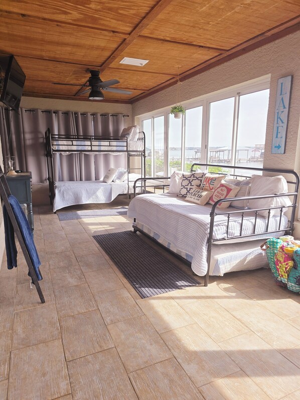 A room with two bunk beds, a desk, and a large window offering a view.