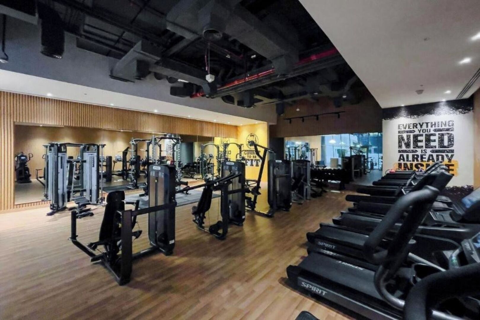 A gym with various exercise equipment, treadmills, and a motivational quote on the wall.