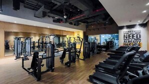 Een sportschool met diverse fitnessapparaten, loopbanden en een motiverende quote op de muur.
