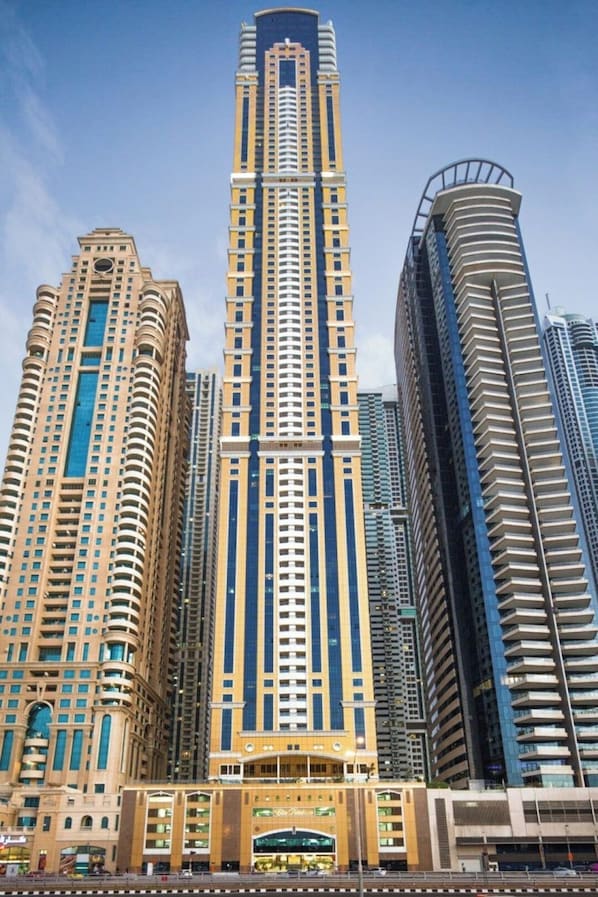 A tall, modern high-rise building with a central core and multiple balconies.