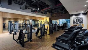 A gym with various exercise machines, treadmills, and a motivational quote on the wall.