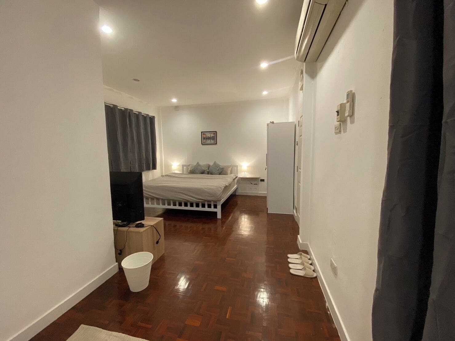Un dormitorio con una cama, un televisor, un balde y una puerta.
