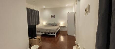 Un dormitorio con una cama, un televisor, un balde y una puerta.
