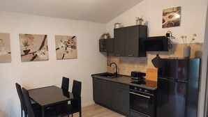 Una cocina compacta con una mesa de comedor y sillas, un refrigerador, una estufa y armarios.