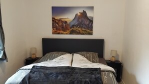 Un dormitorio con cama, mesitas de noche y un cuadro colgado en la pared.