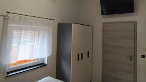 Una habitación con ventana cubierta por una cortina translúcida, un armario blanco y una puerta cerrada.