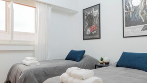 A hotel room with two beds, grey bedding, white towels, a pineapple, and movie posters on the wall. - MOT Juncal 2800 (Buenos Aires)